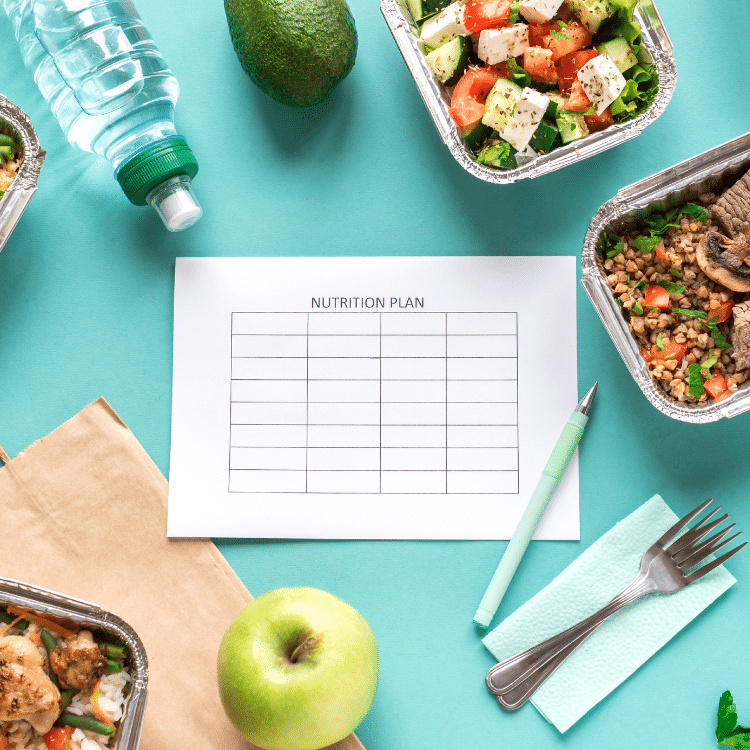 A nutrition plan beside prepared vegetables and colorful meals